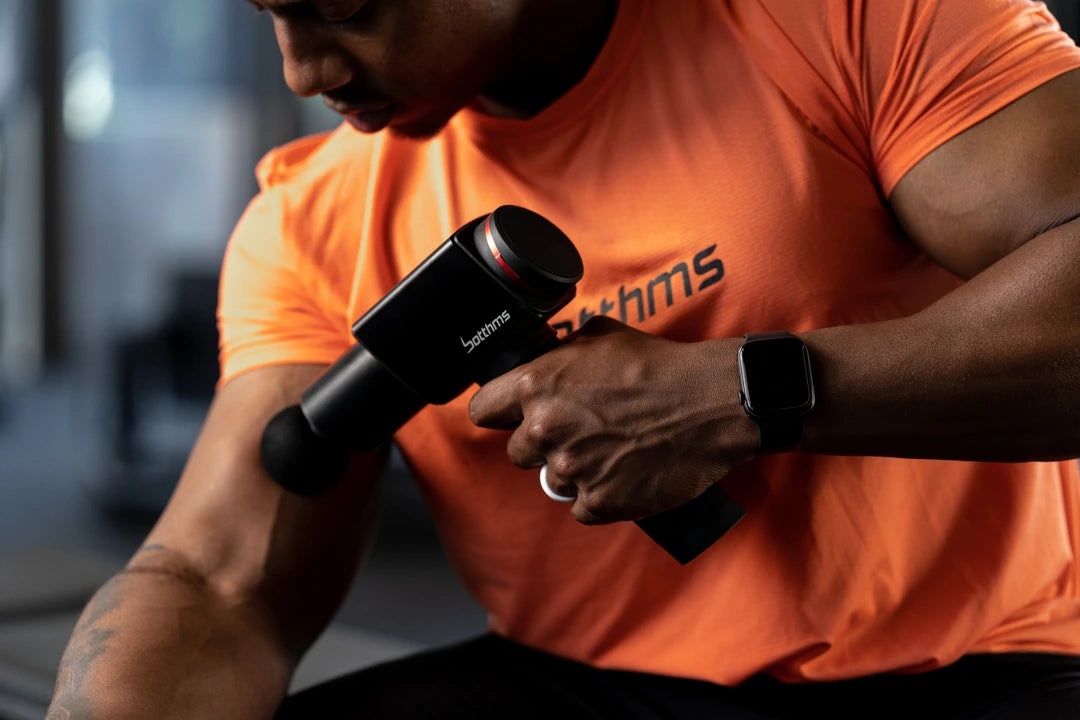 man applying botthms massage gun on his right arm muscle