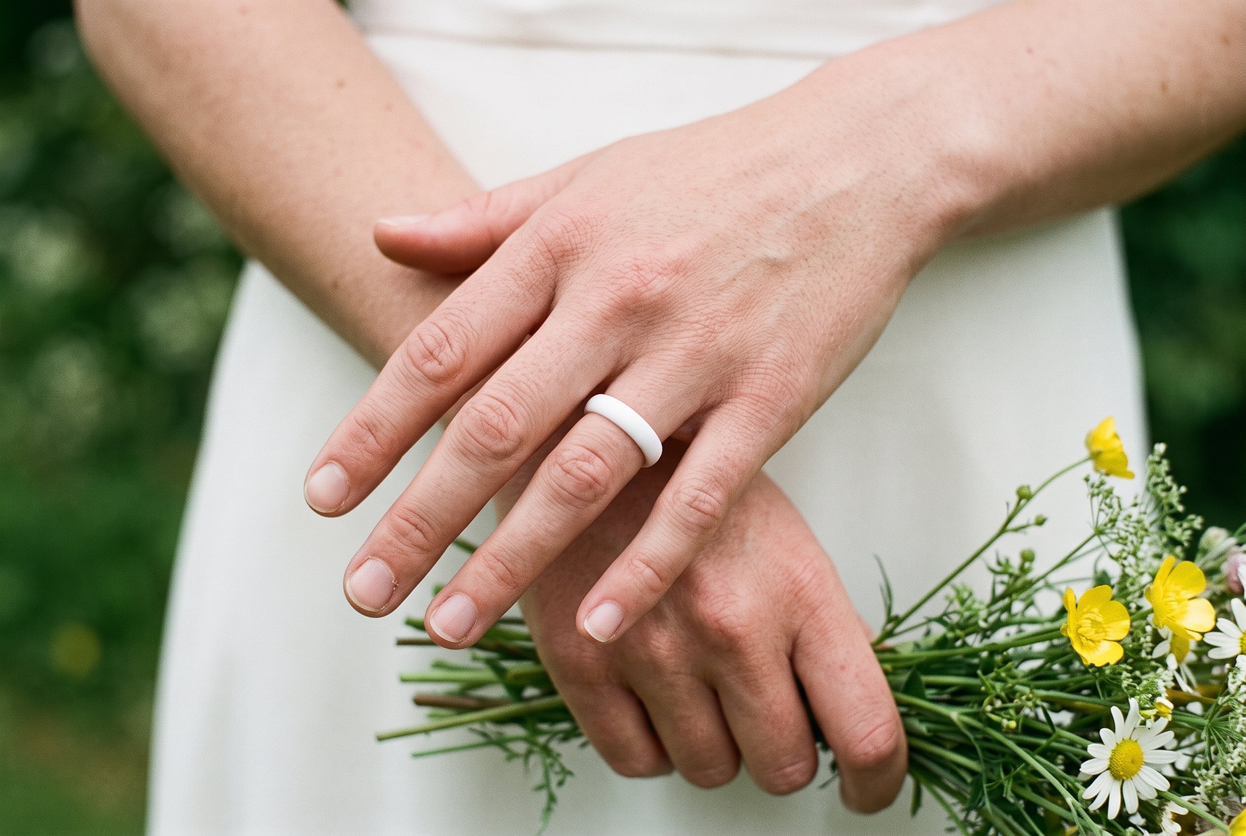 White women's silicone ring worn by a bride holding a small wildflower bouquet