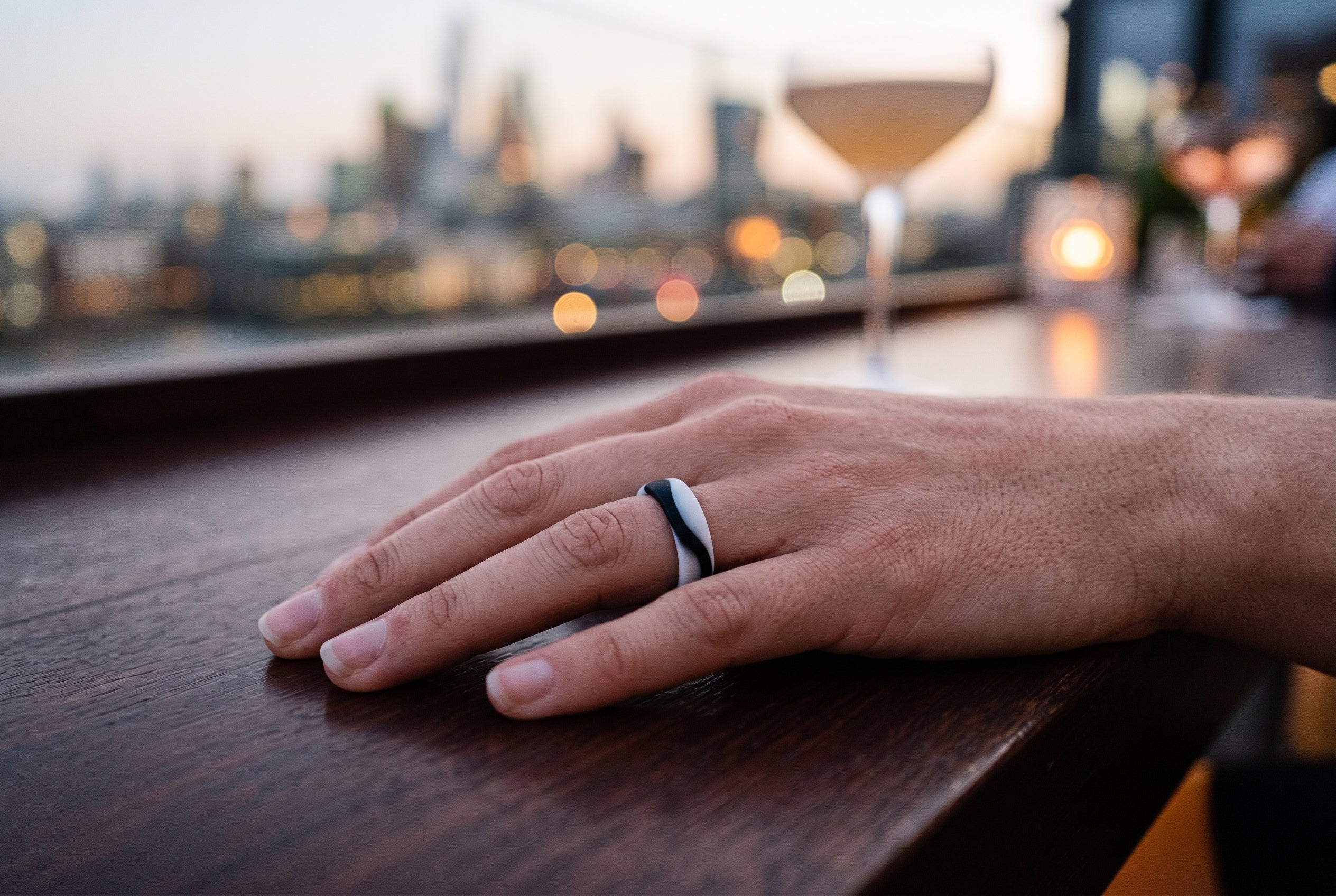 Black and white flow women's silicone ring worn at a London rooftop bar at dusk
