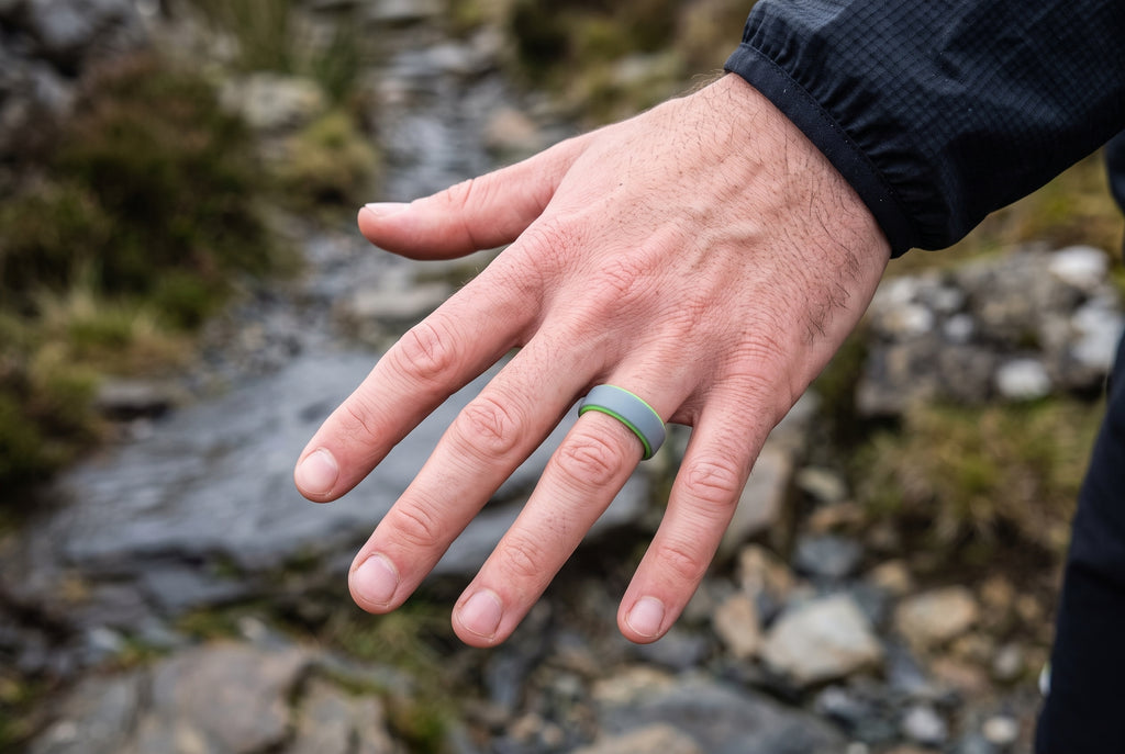 Grey men's silicone ring with lime green inner edge worn on a rocky Snowdonia trail
