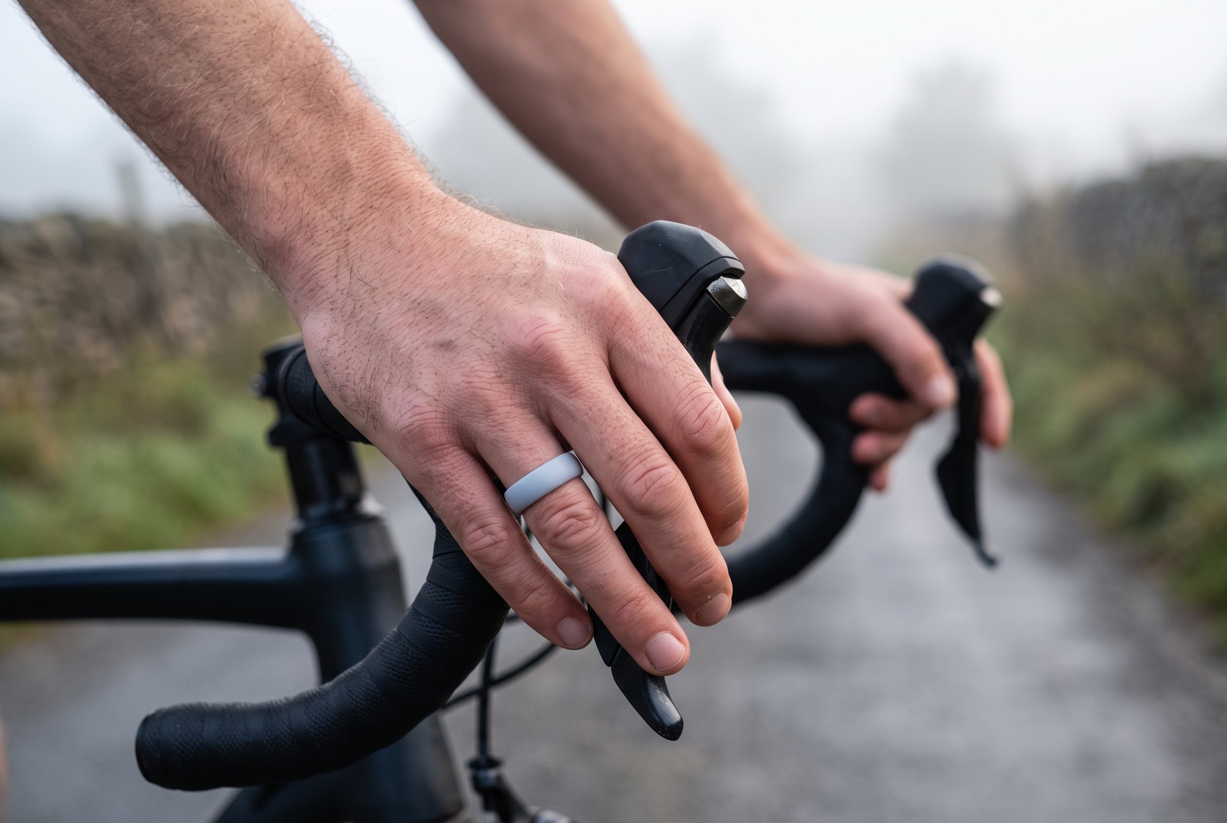 Grey men's silicone ring worn on road bike handlebars on a misty Peak District lane