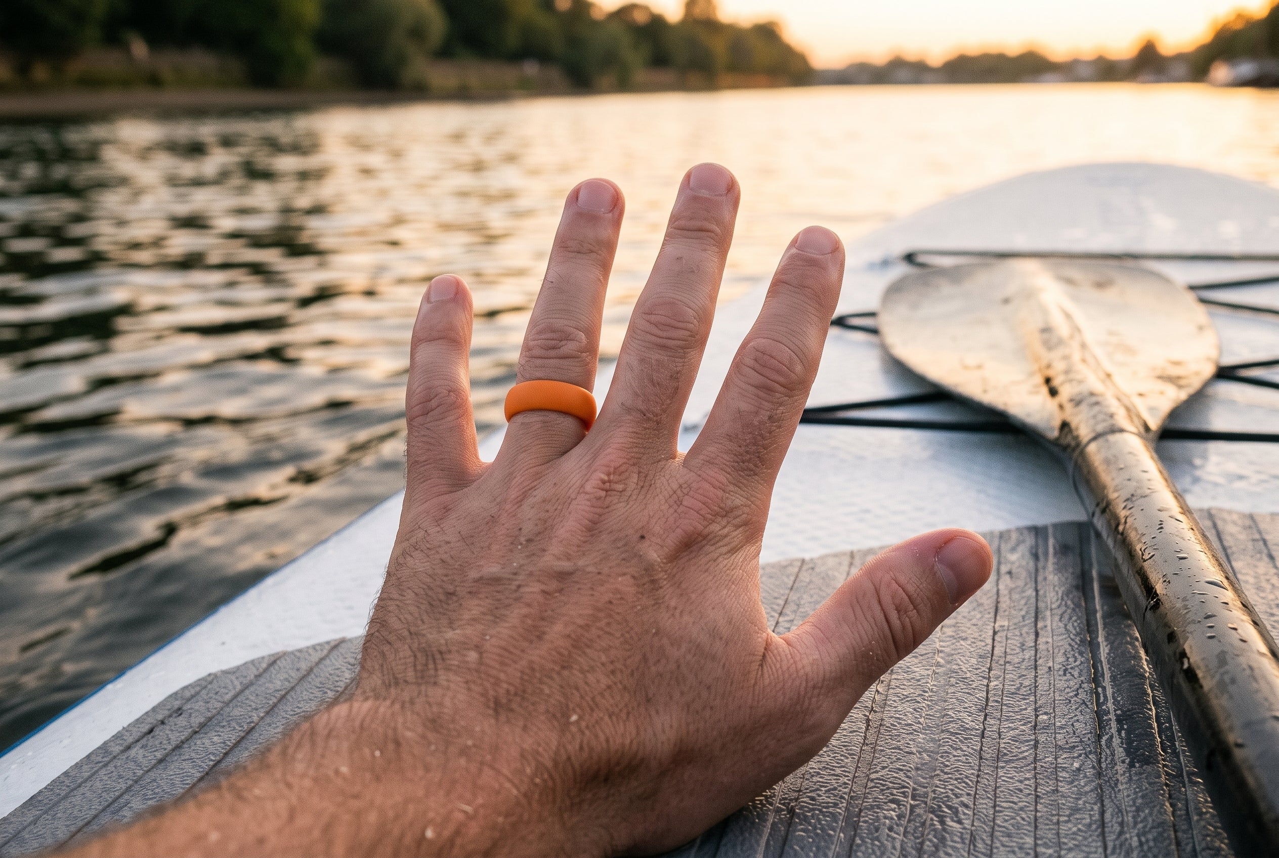 Orange men's silicone ring worn on a paddleboard on the Thames at sunset