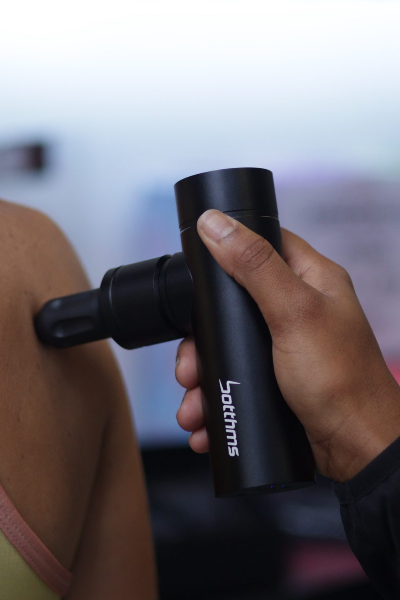 man applying botthms massage gun on the back of another person