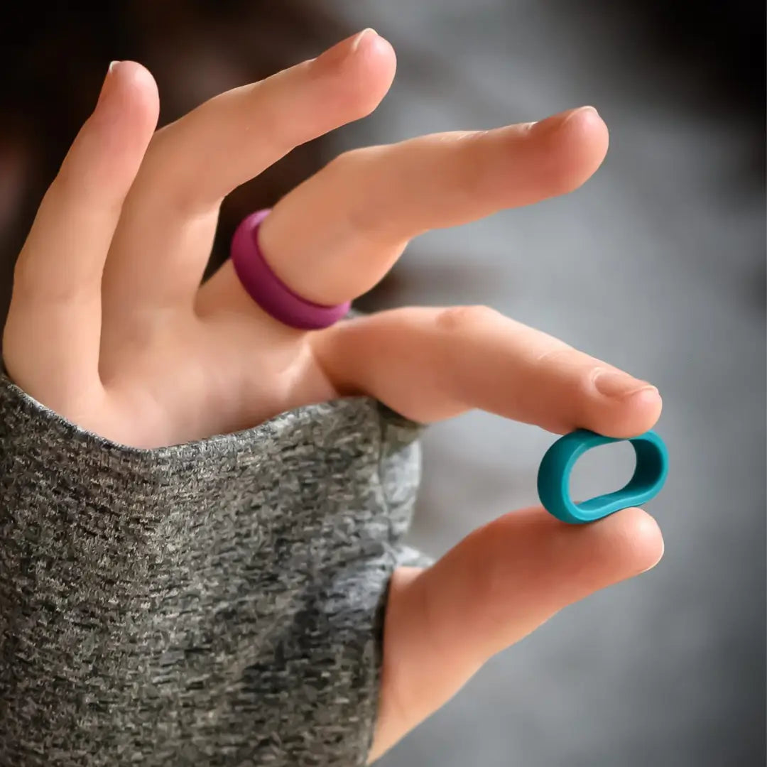 Hand wearing botthms red silicone ring and showing turquoise silicone ring