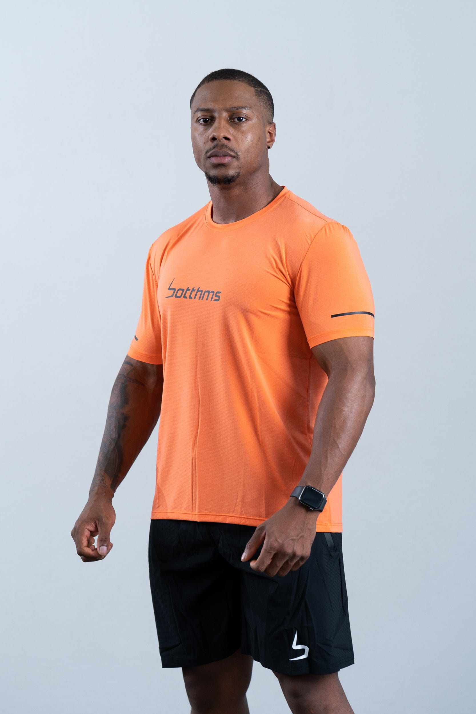 athlete wearing botthms orange sport t-shirt - front left full view