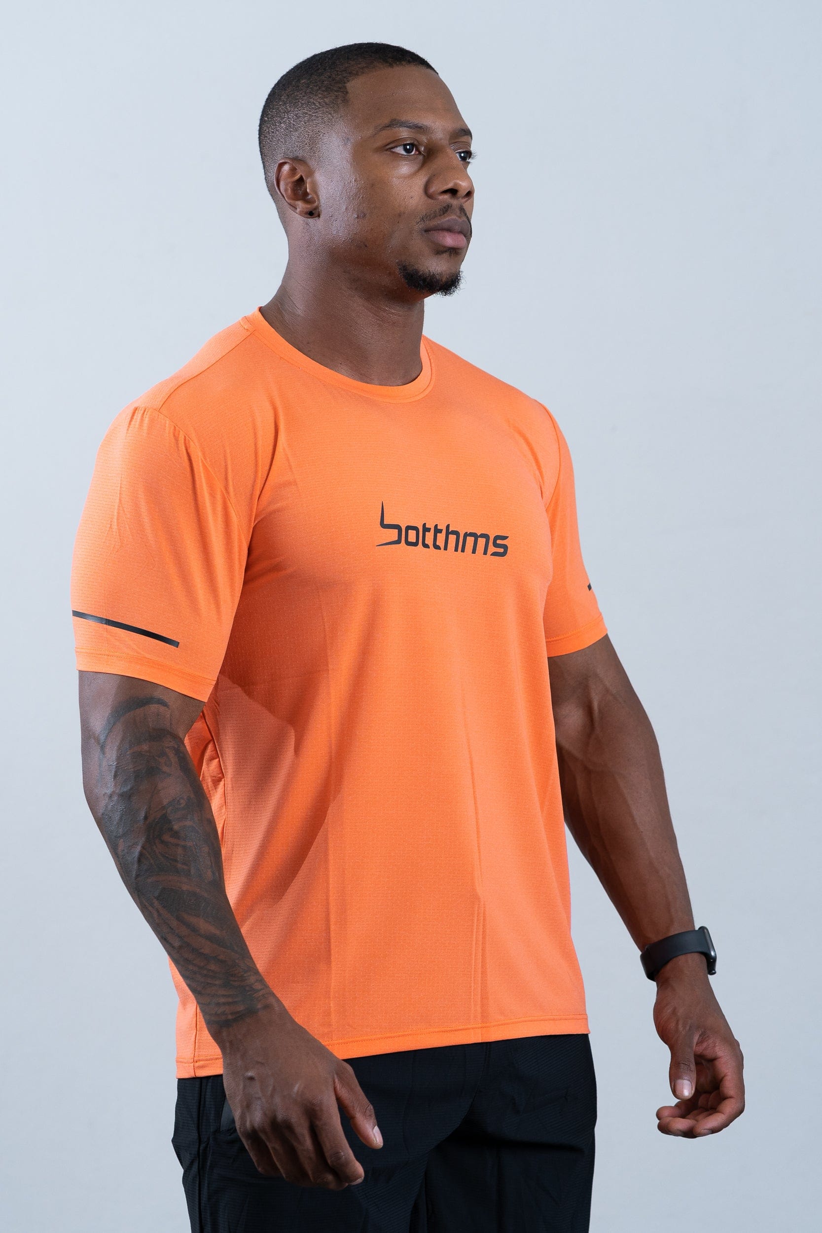 athlete wearing botthms orange sport t-shirt - front right view