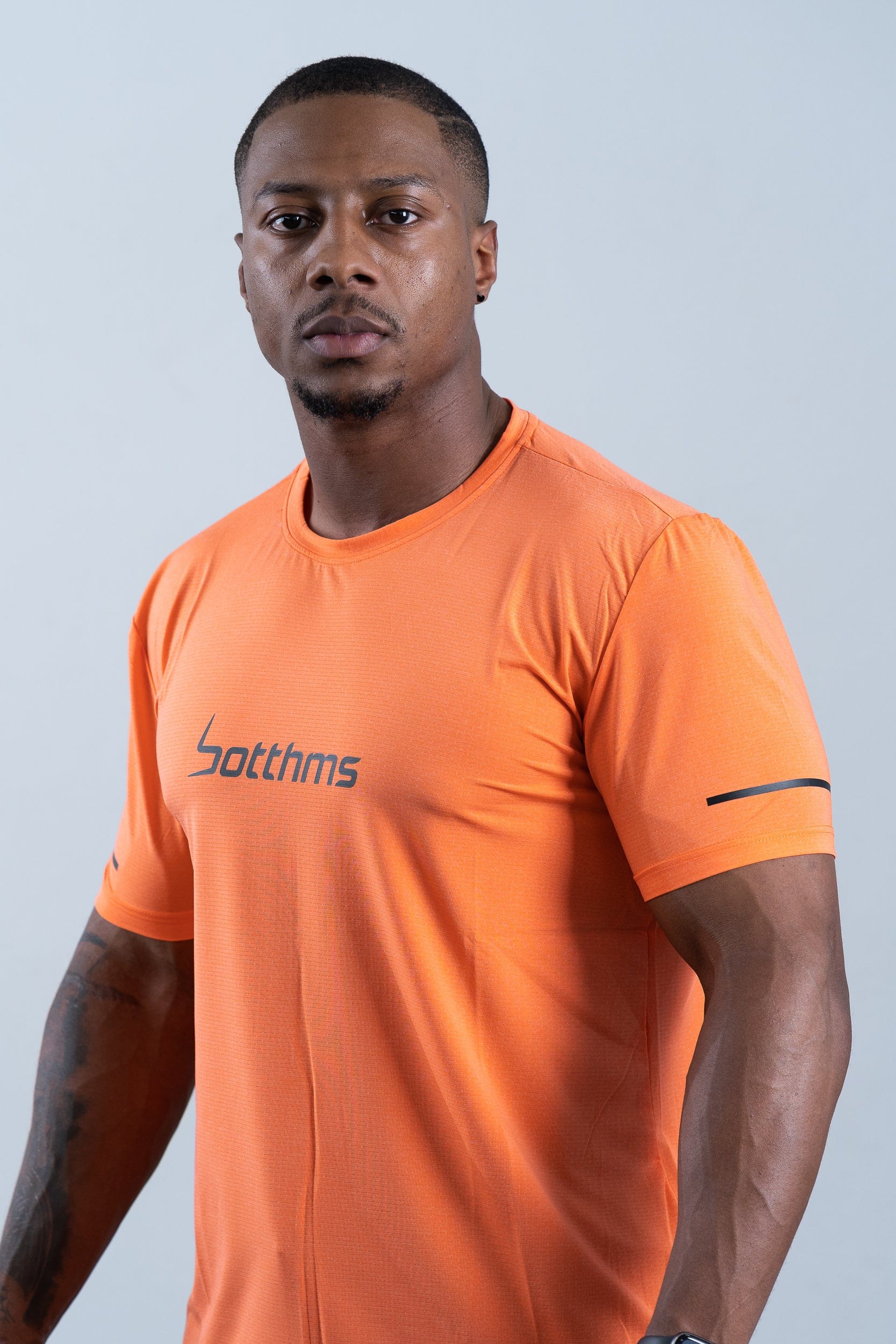 athlete wearing botthms orange sport t-shirt - front left closeup view