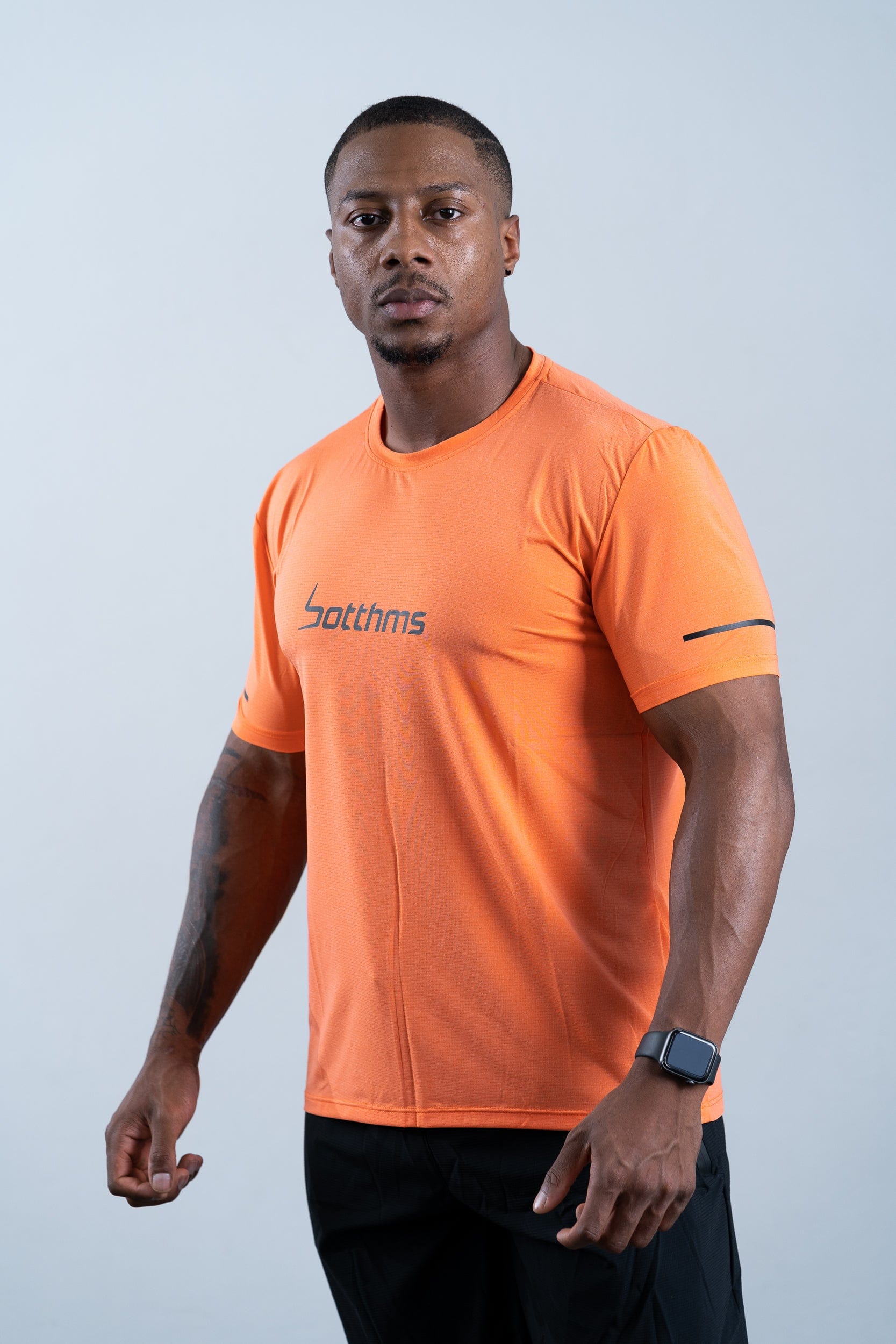 athlete wearing botthms orange sport t-shirt - front left view