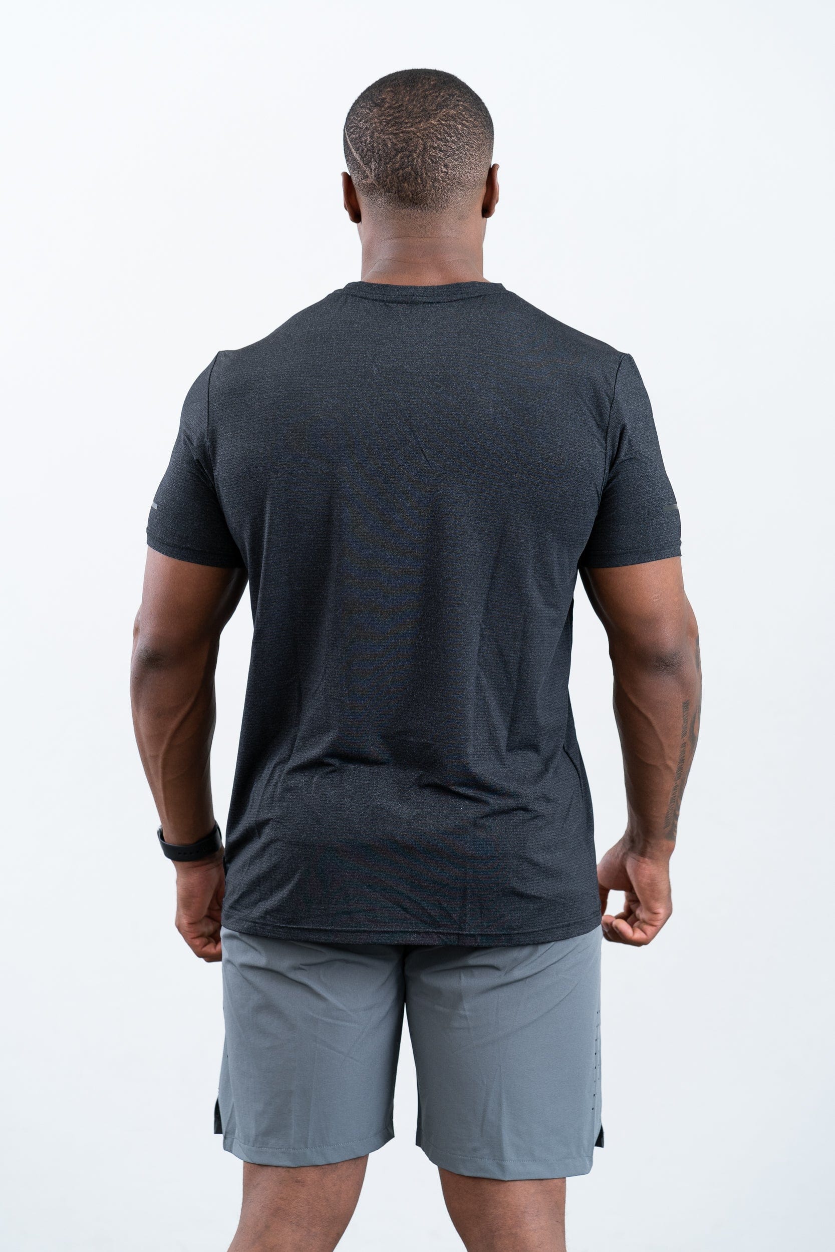 man standing wearing botthms black sport t-shirt- rear view