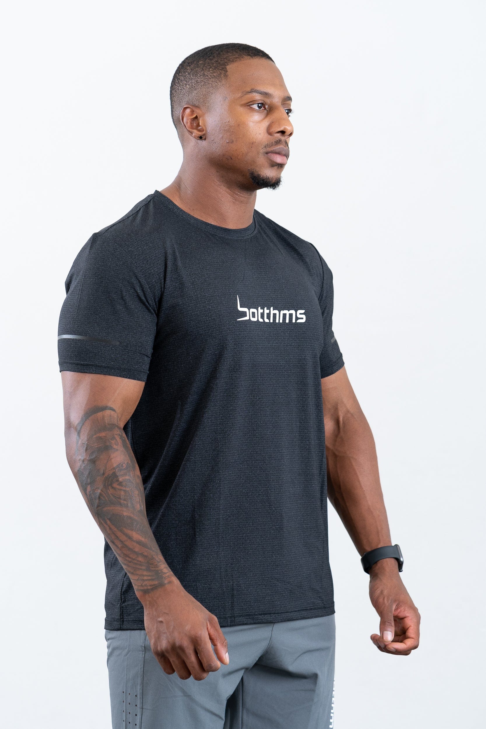man standing wearing botthms black sport t-shirt- angled front-right view